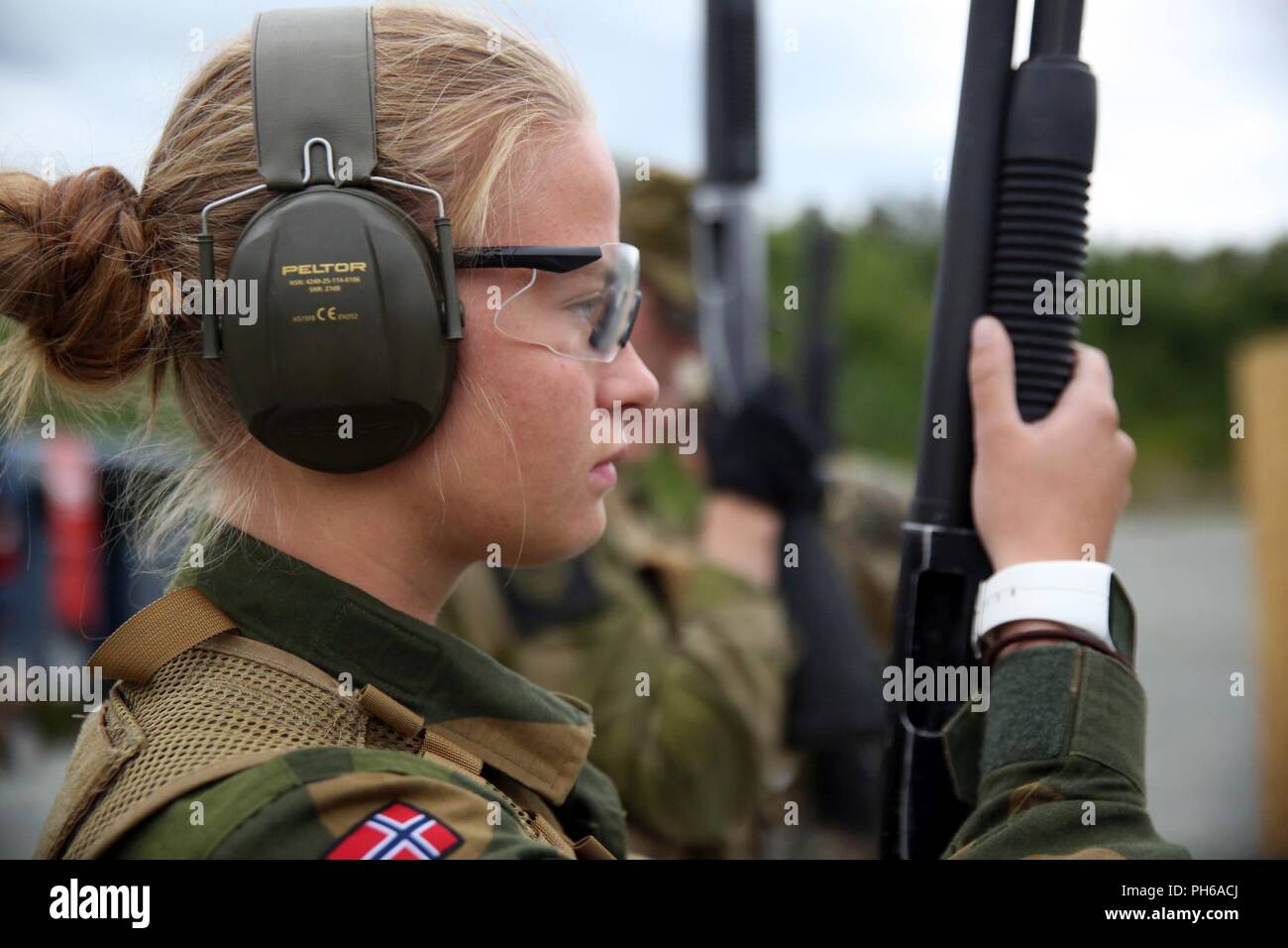 A Norwegian military policeman prepares to fire an M500 shotgun during a shotgun range at Leksdal Skytefelt Training Complex, Norway, June 28, 2018. The multinational training allowed the service members to cross-train with American and Norwegian weapon systems including assault rifles, shotguns, and pistols. The Marines and Norwegian soldiers practiced firing from the kneeling and standing positions while moving between barricades. Stock Photo