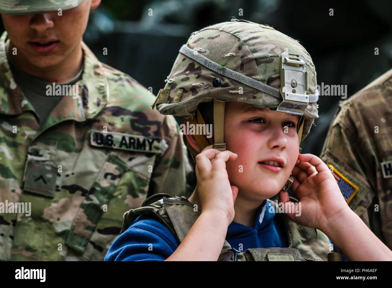 A Polish child tries on a Kevlar helmet from the 1st Squadron, 2nd Cavalry Regiment during a static display with Battle Group Poland at Giżycko, Poland on June 30, 2018. Battle Group Poland is a unique, multinational coalition of U.S., U.K., Croatian and Romanian Soldiers who serve with the Polish 15th Mechanized Brigade as a deterrence force in support of NATO’s Enhanced Forward Presence. Stock Photo