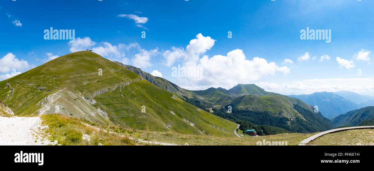 Wide shot panorama of several mountains green summertime with blue sky appennini Italy Stock Photo