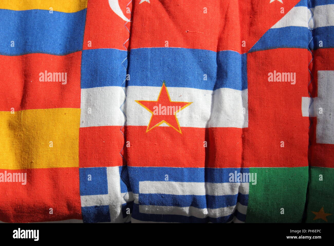 Yugoslavian flag amongst other world flags on an old flag patterned sleeping bag. Stock Photo