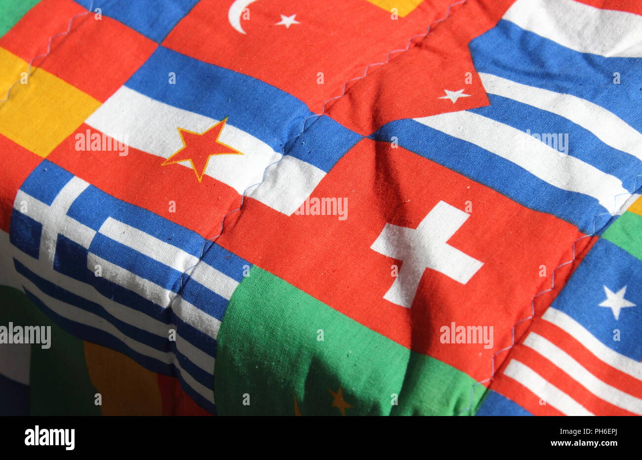 Yugoslavian flag amongst other world flags on an old flag patterned sleeping bag. Stock Photo
