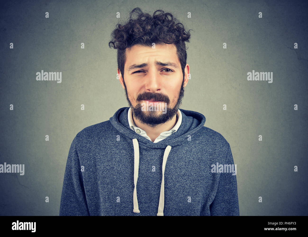 Handsome young beard man looking dubious and curious on gray background Stock Photo