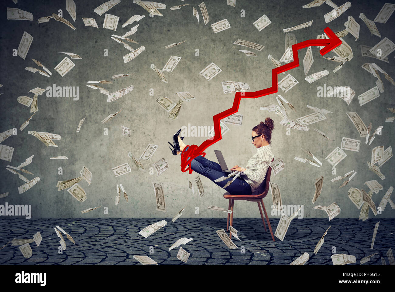 Concept side view shot of businesswoman using laptop on chair among flying money bills and growing red arrow on gray background Stock Photo