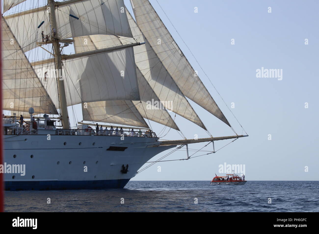 Clipper ship under full sail at sea with a tender off the bow Stock Photo