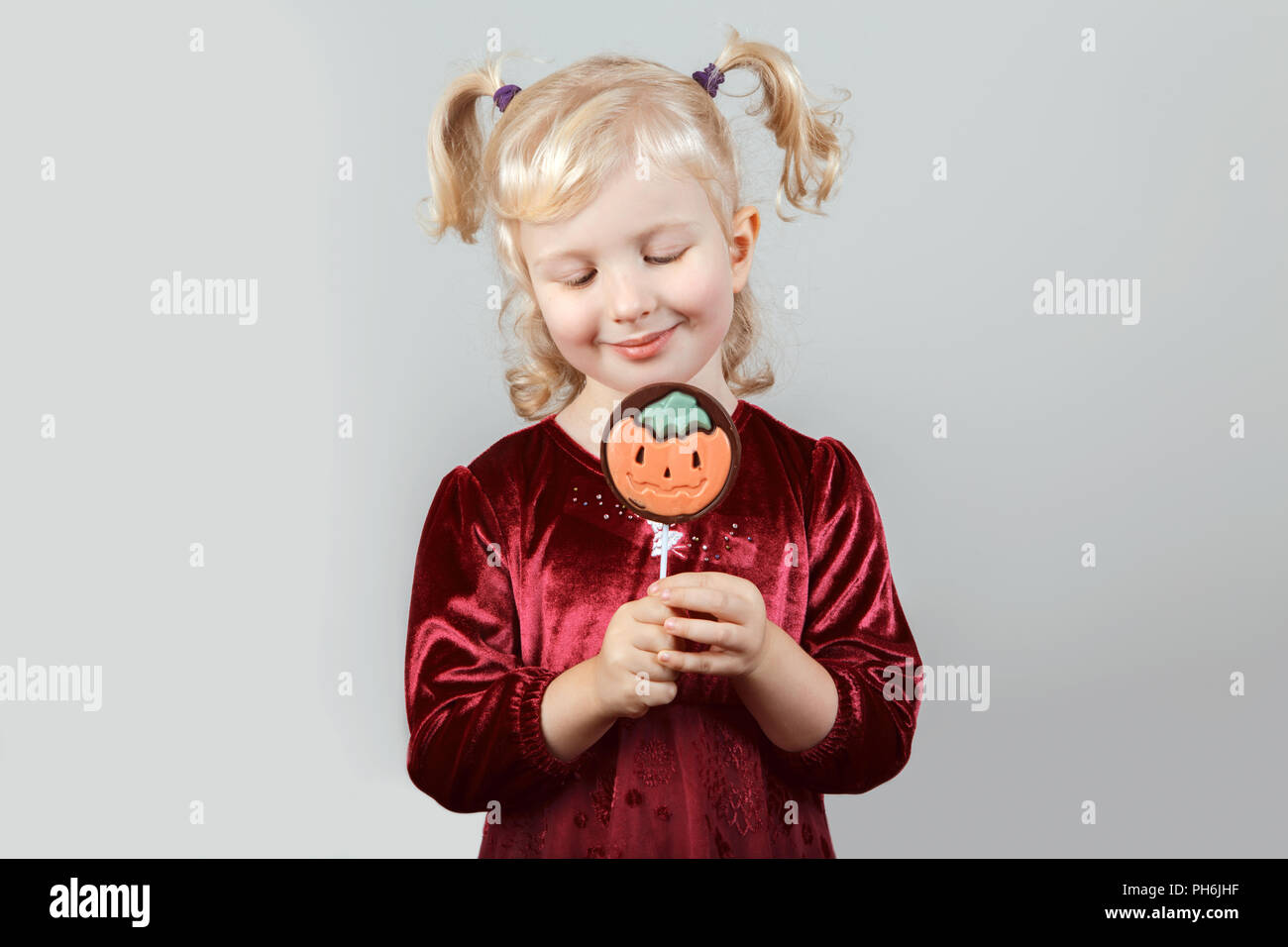 Portrait of adorable funny white blonde Caucasian girl with pigtails dressed for Halloween. Child playing having fun in studio for autumn fall seasona Stock Photo