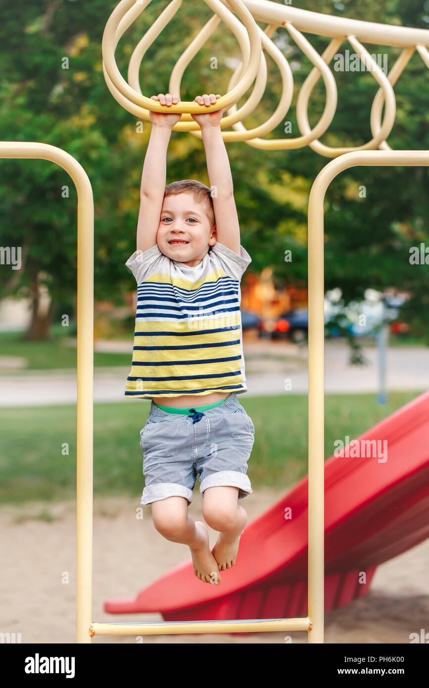 Young Caucasian boy hanging on monkey bars in park on playground