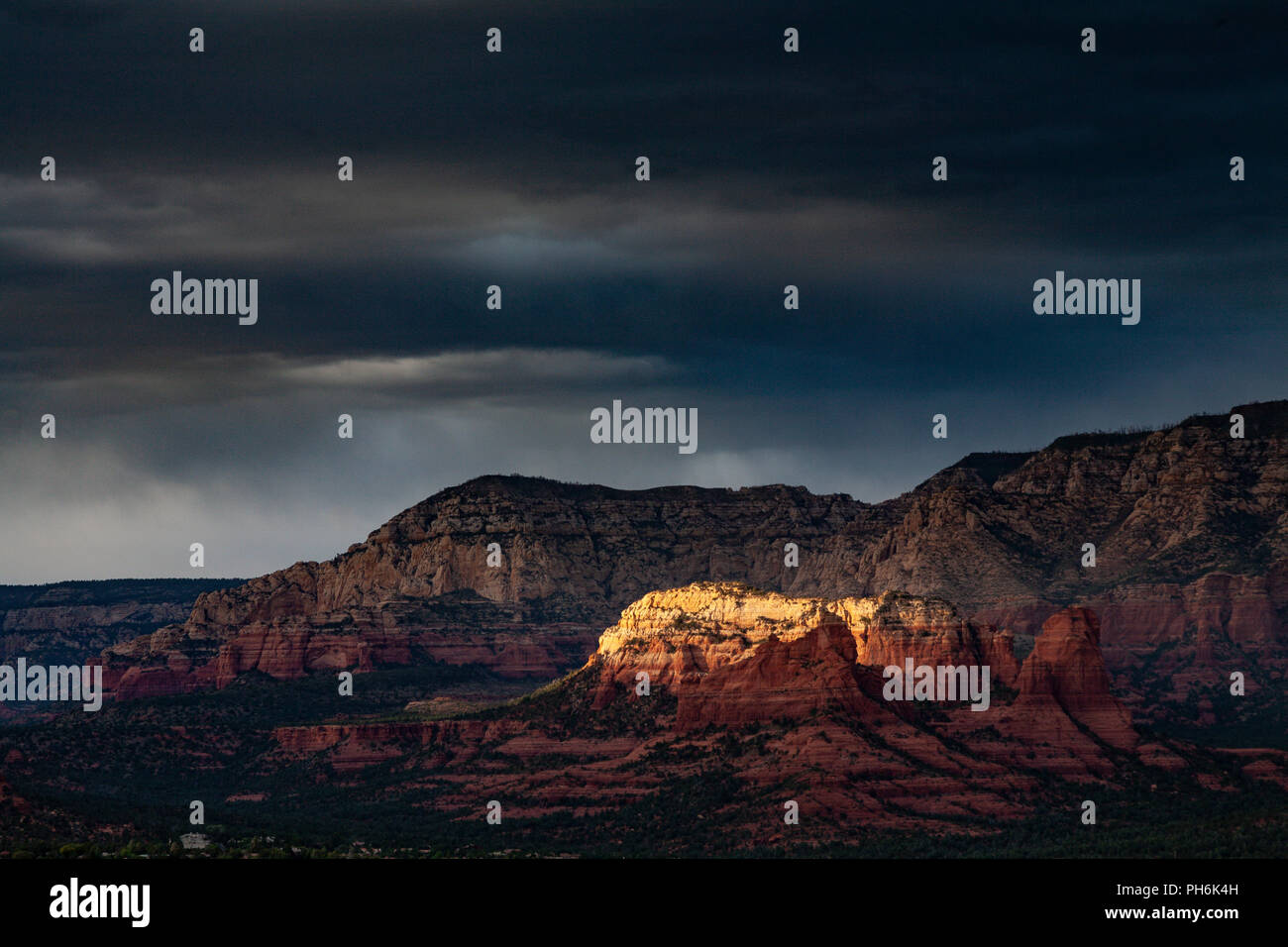 Sunlight on sandstone butte at Sedona, Arizona, USA under stormy skies Stock Photo