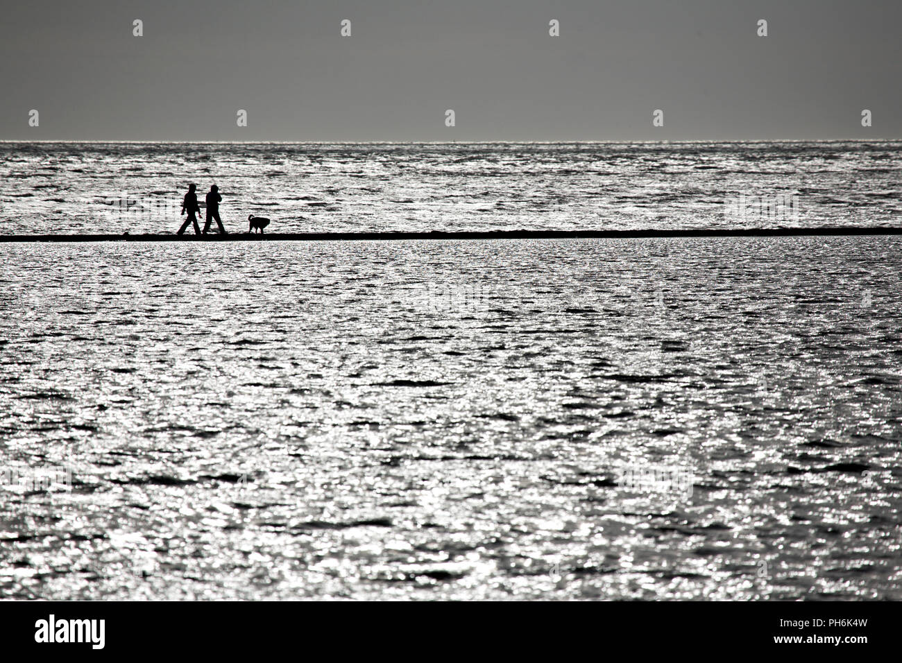 Couple and dog on the causeway around the Marine Lake at West Kirby, Wirral, England Stock Photo