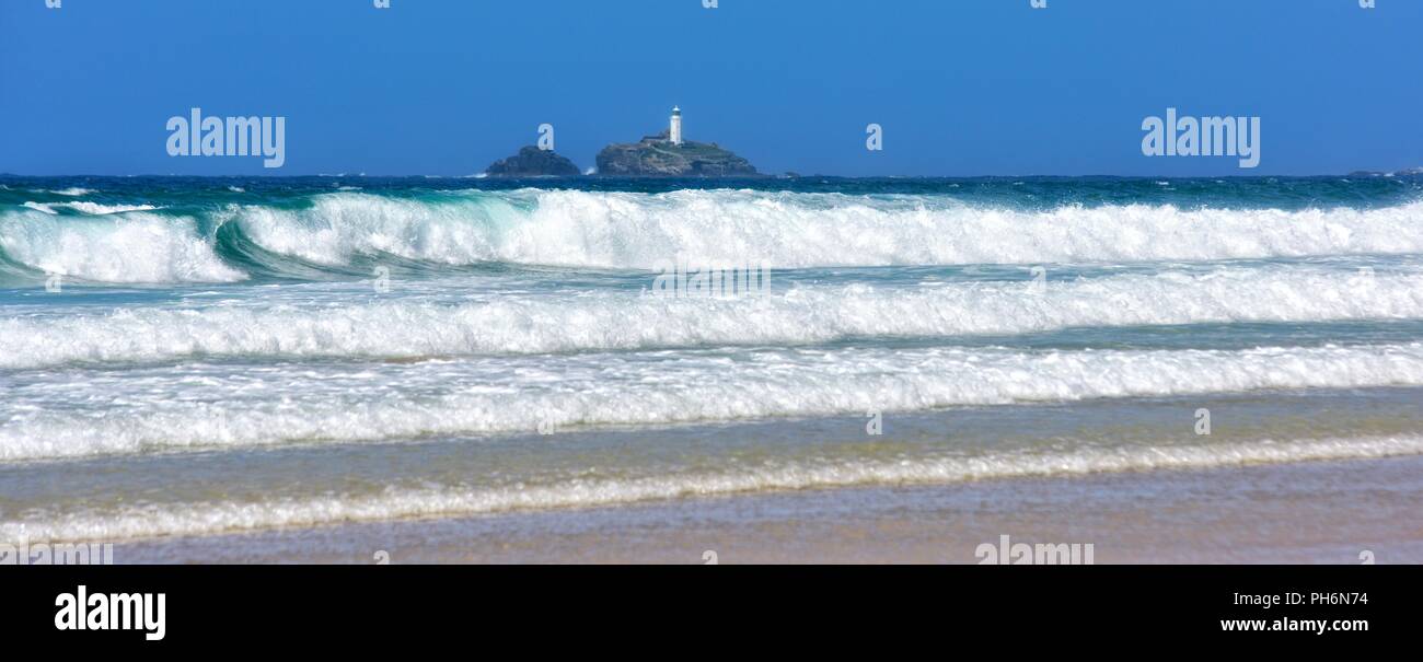 Waves rolling in on Riviere Towans beach with Godrevy lighthouse in the