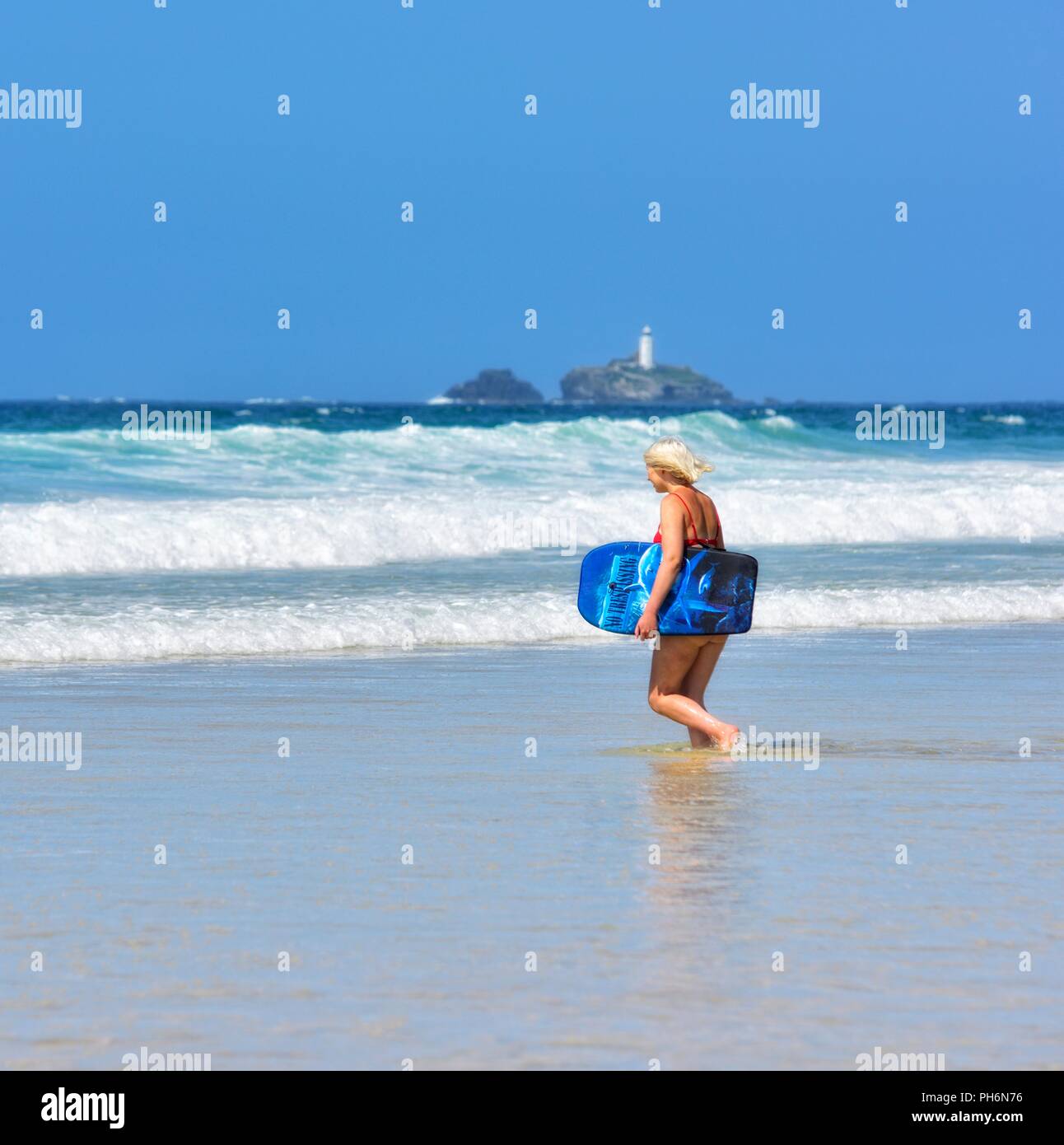 Blond woman walking into the sea with a body board,Riviere Towans beach