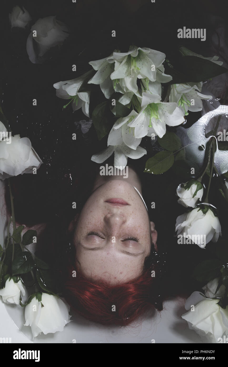 Relaxing, Teen submerged in water with white roses, romance scene Stock