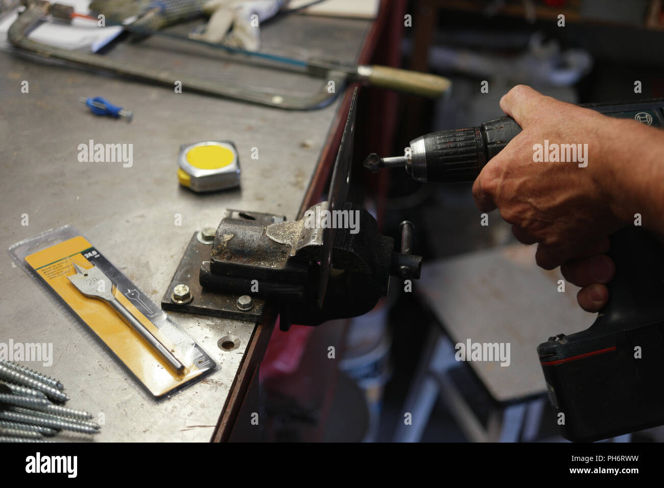 Laborer using an electric drill while metalworking Stock Photo