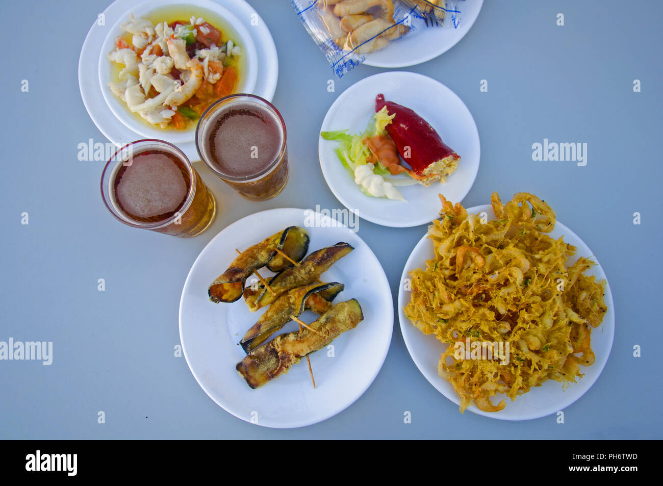 Two beers, white plates with different snacks, summer Stock Photo