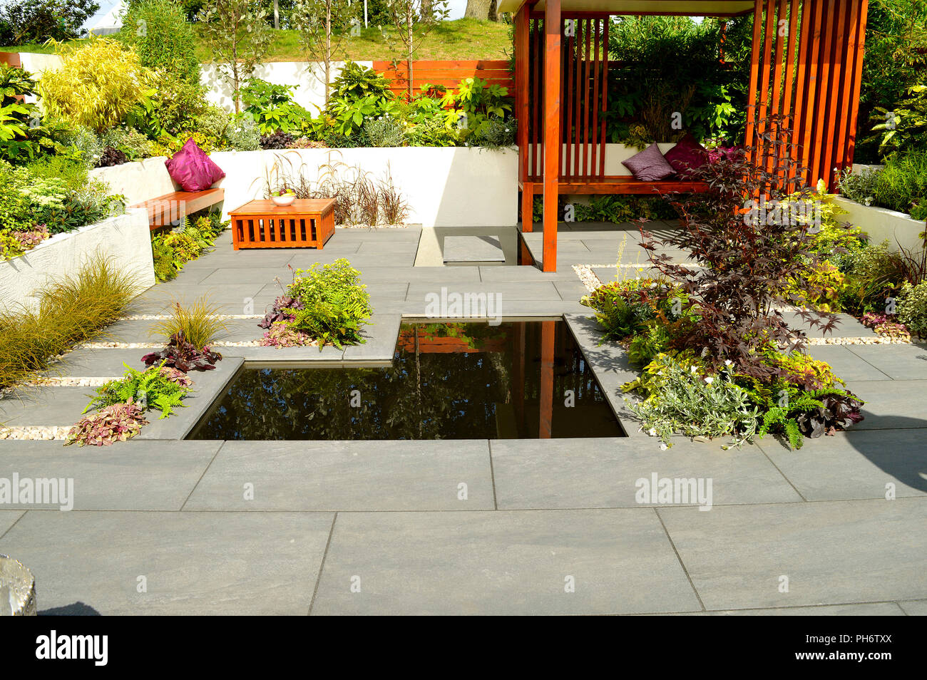 Low maintenance garden with a stone patio and ornamental garden pond Stock Photo