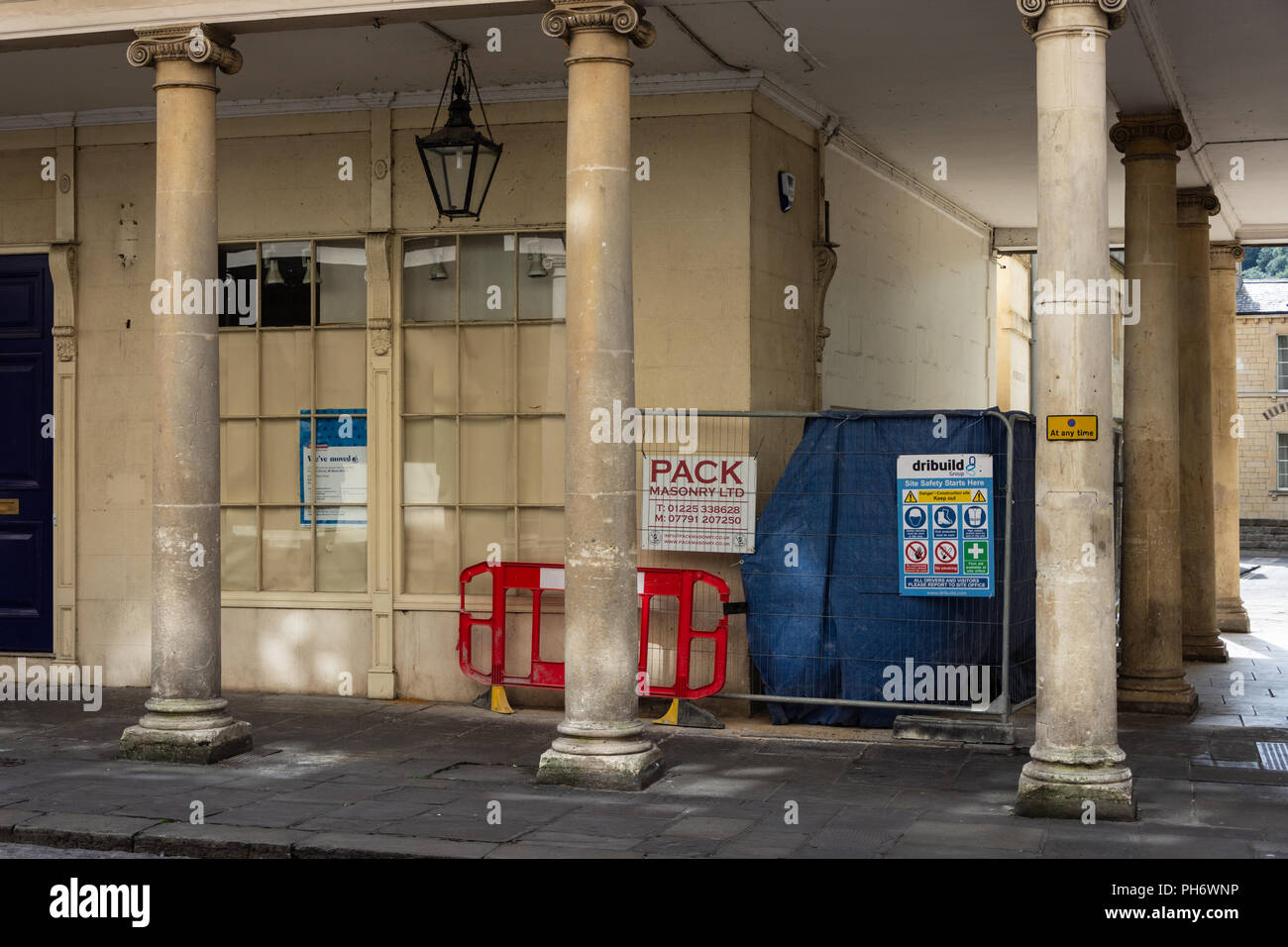 A bath building including ionic column with safety barriers and notices of building work being done Stock Photo