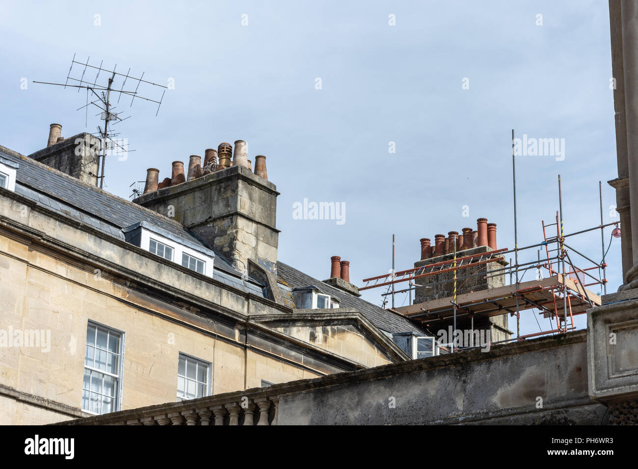 A rooftop in the city of Bath with TV ariels and scaffolding around a chimney stack with multiple chimney pots Stock Photo