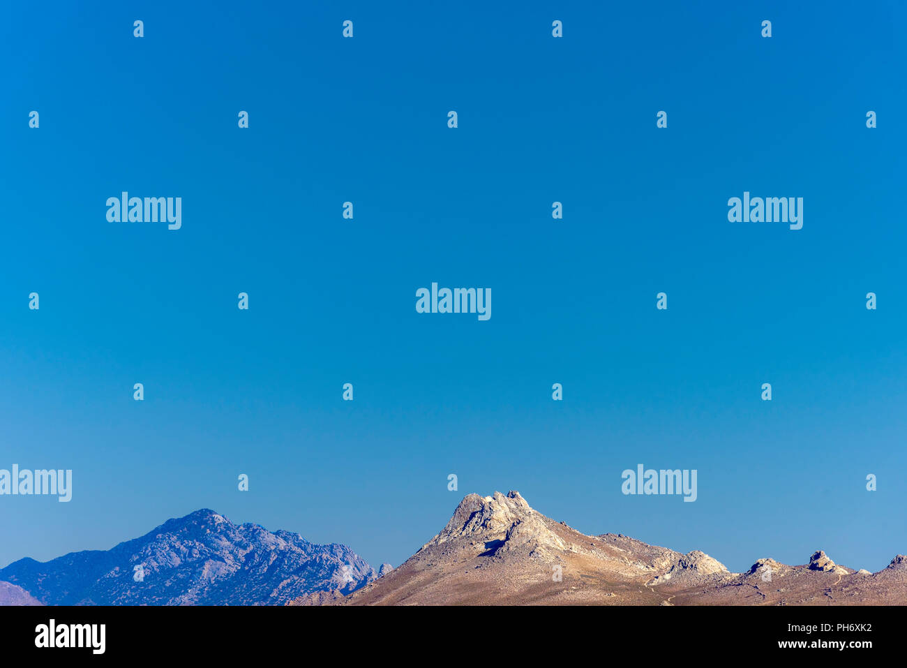 Barren desert mountain peaks under a bright blue sky Stock Photo - Alamy