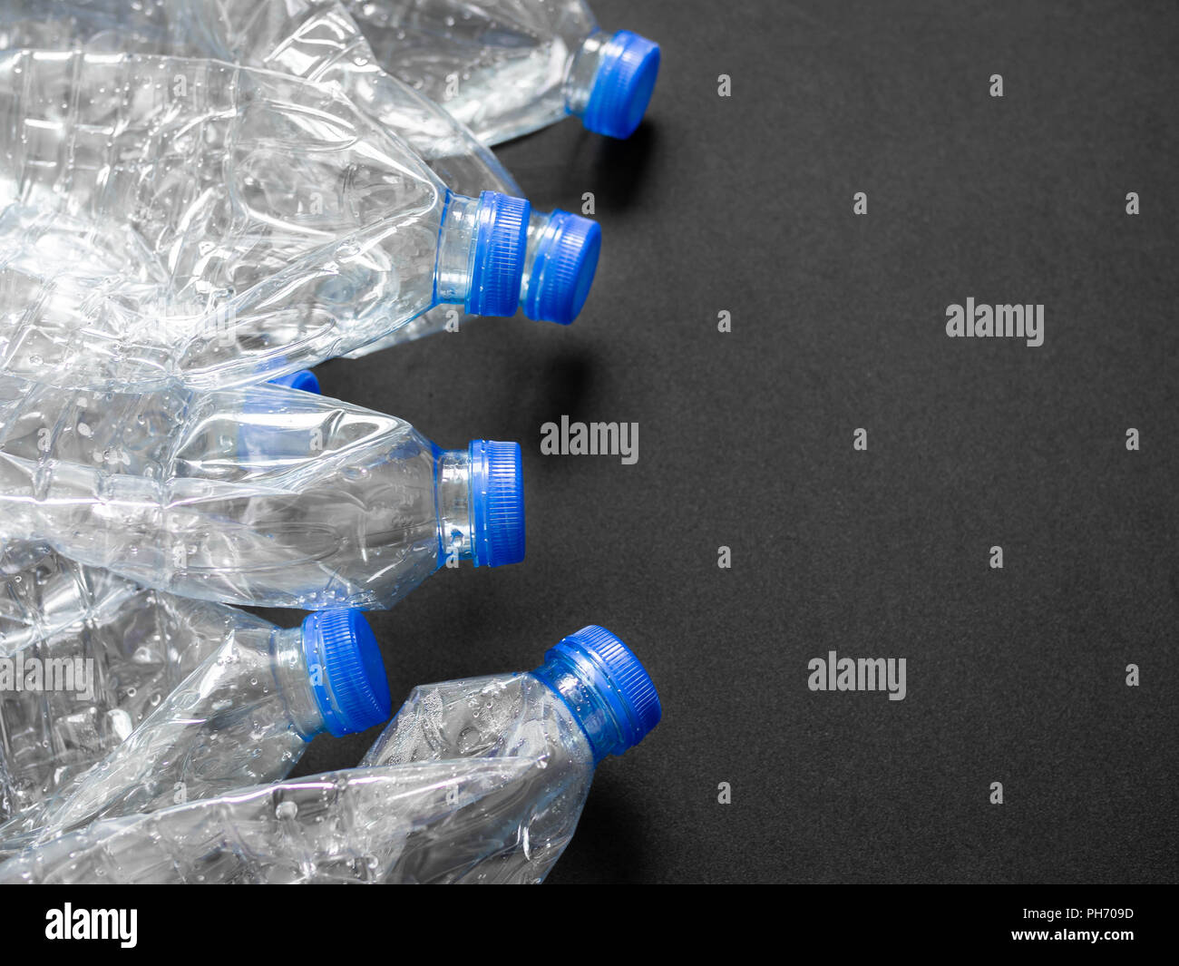 Empty crushed recycle clear plastic drink water bottles on black