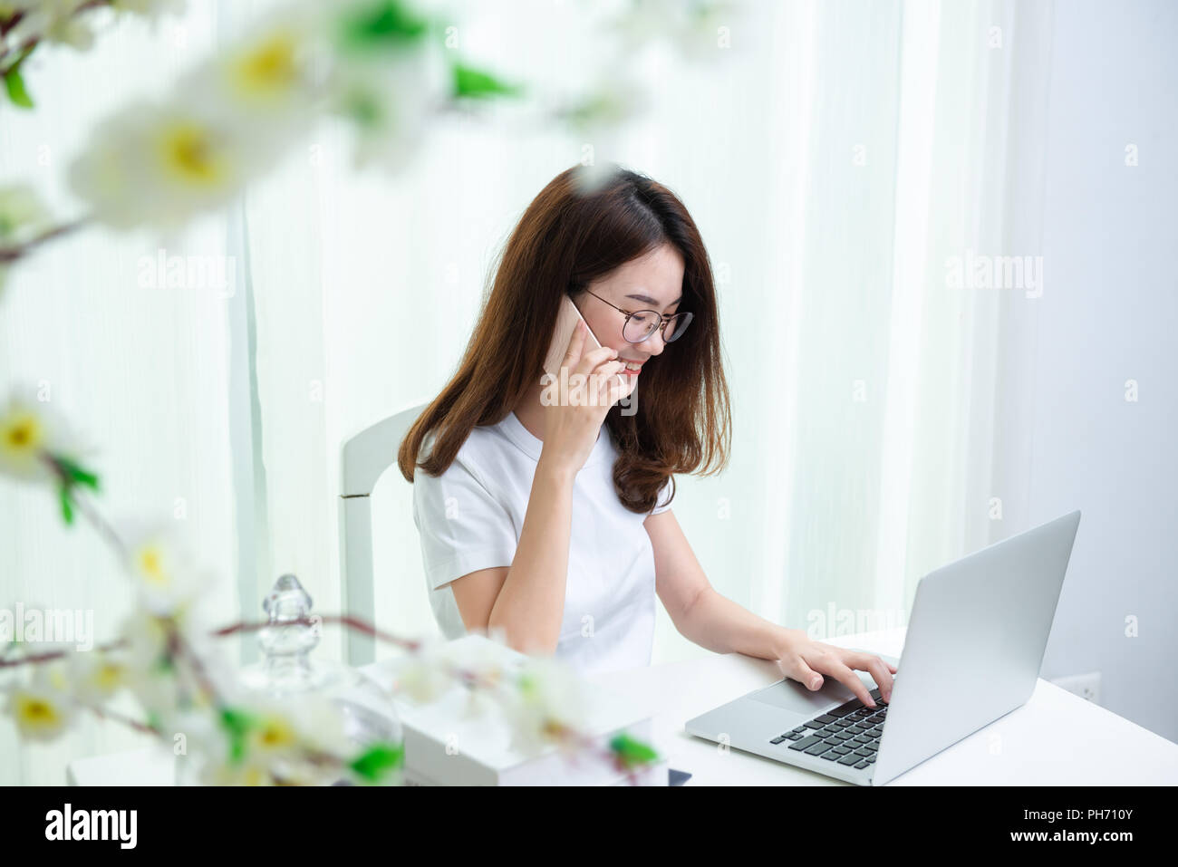 Young asian girl is freelancer with her private business at home office, Working with laptop and smartphone Stock Photo