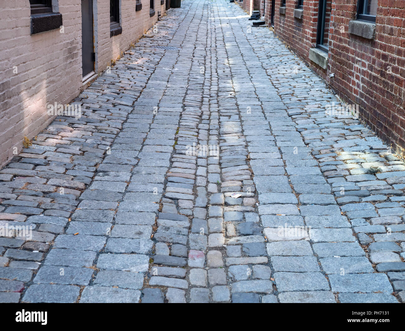 Cobblestone street in the daytime moving through a brick alleyway Stock Photo