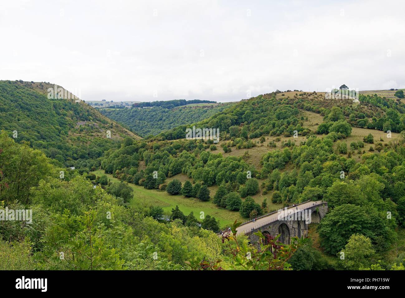 Capturing the awesome scale of the green and fertile Monsal valley that dwarfs an extensive railway viaduct, in the Peak District. Stock Photo