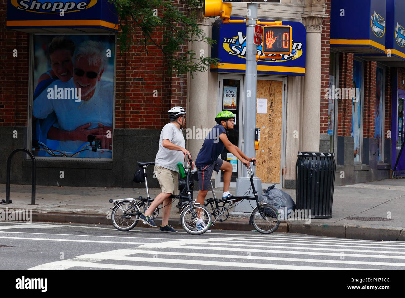 Cyclists on Brompton folding bicycles stopped at a traffic light Stock Photo