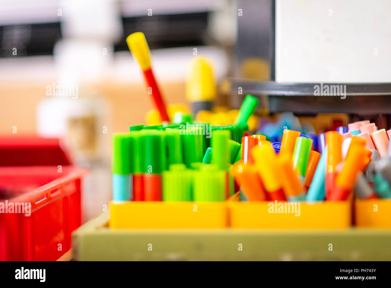 Close up image of pots of coloured pens and crayons in a school art classroom Stock Photo