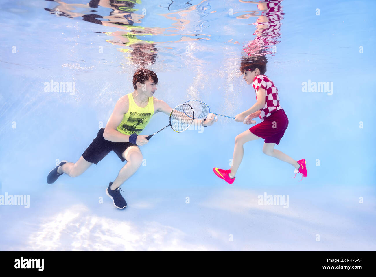 Two teenagers playing badminton underwater Stock Photo