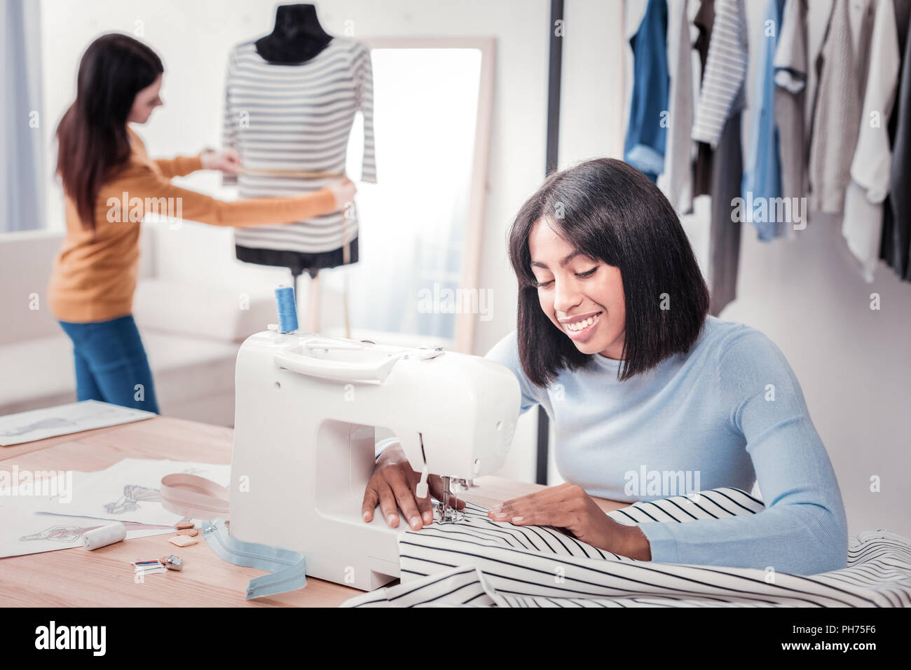 Cheerful seamstress working in personal studio Stock Photo