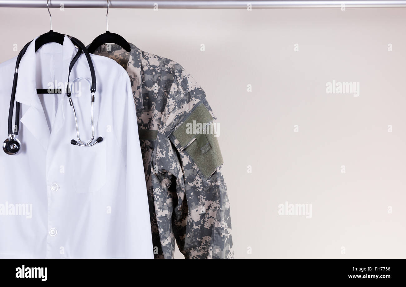 Medical white consultation coat and military uniform on hanger Stock Photo