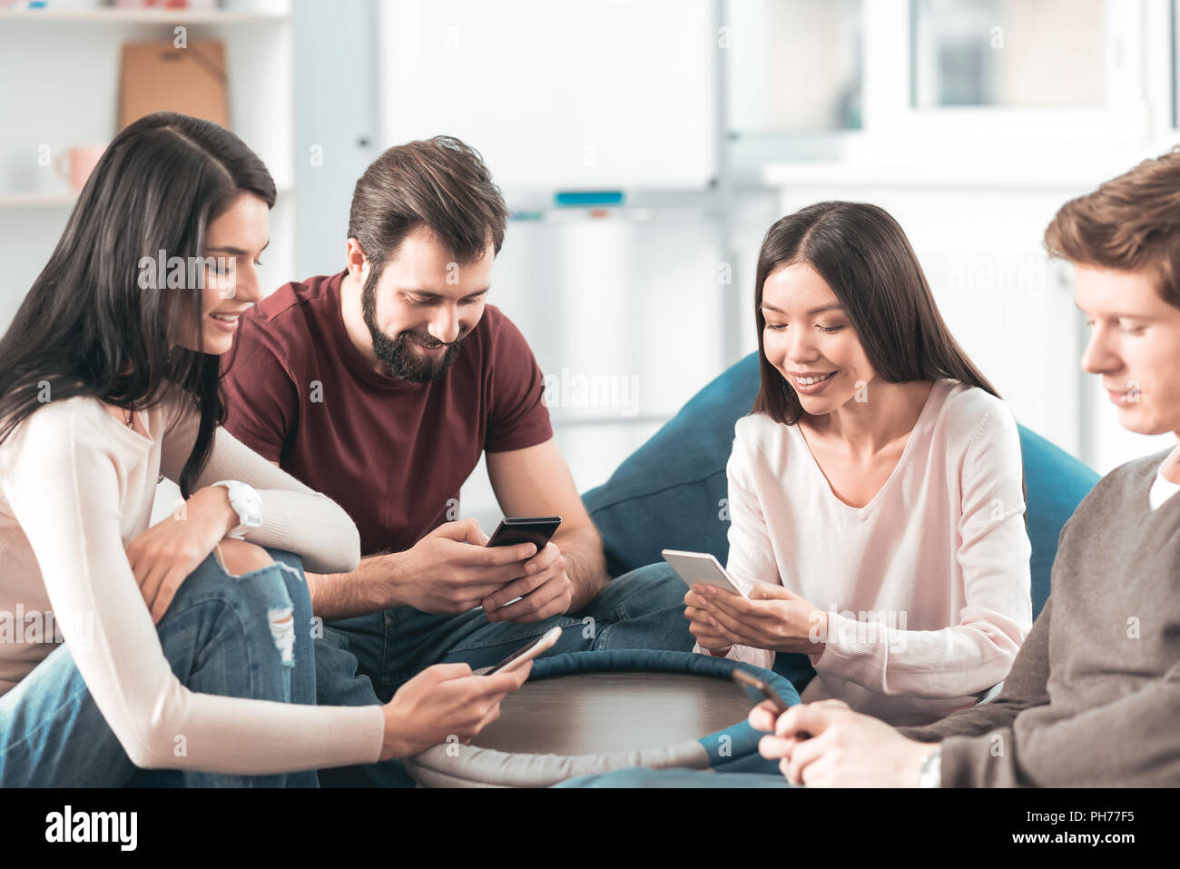 Positive friends using smartphones hi-res stock photography and images ...