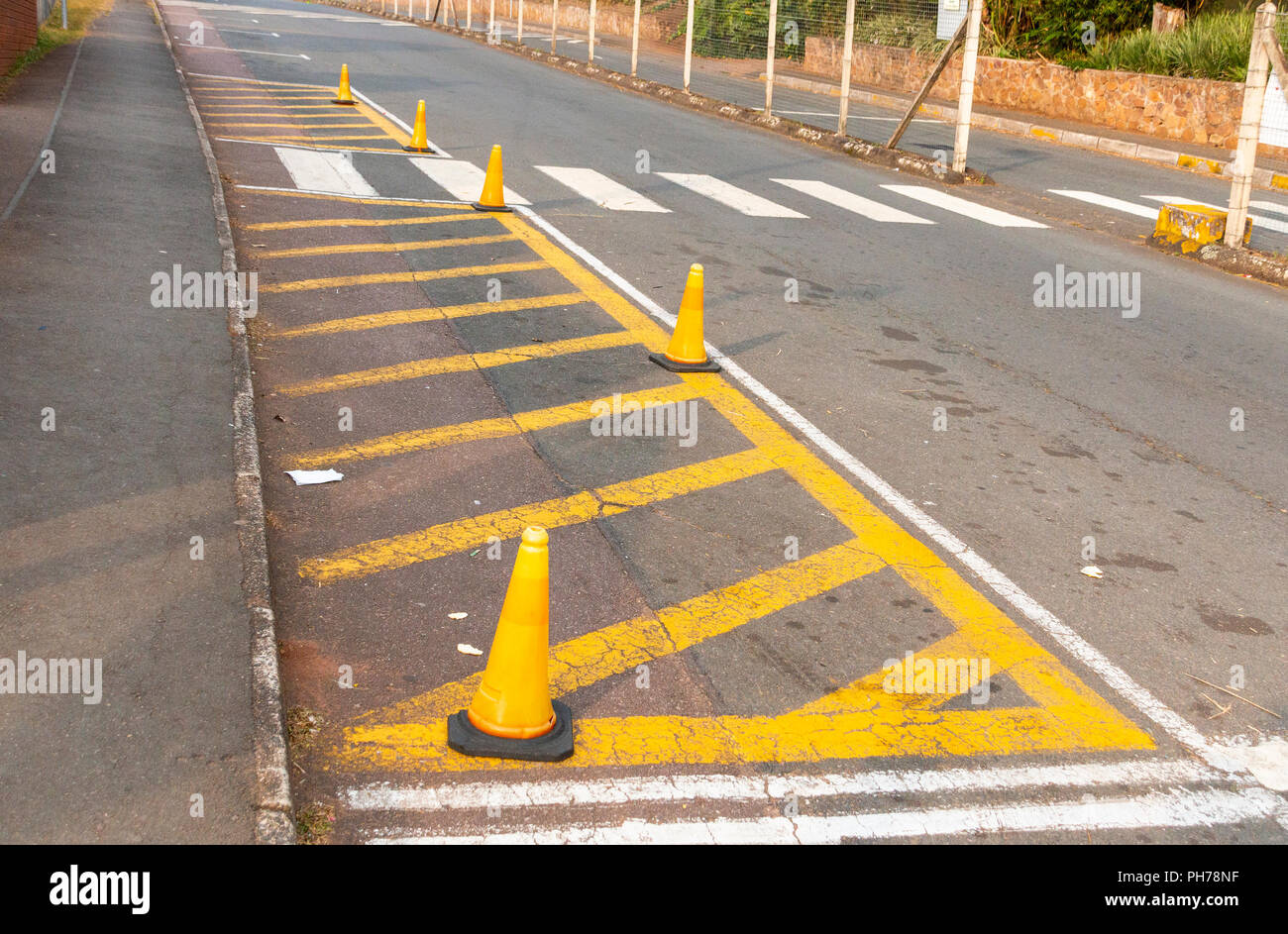 A painted island outside a preschool conered off by orange road cones next to a zebra crossing between two busy roads Stock Photo
