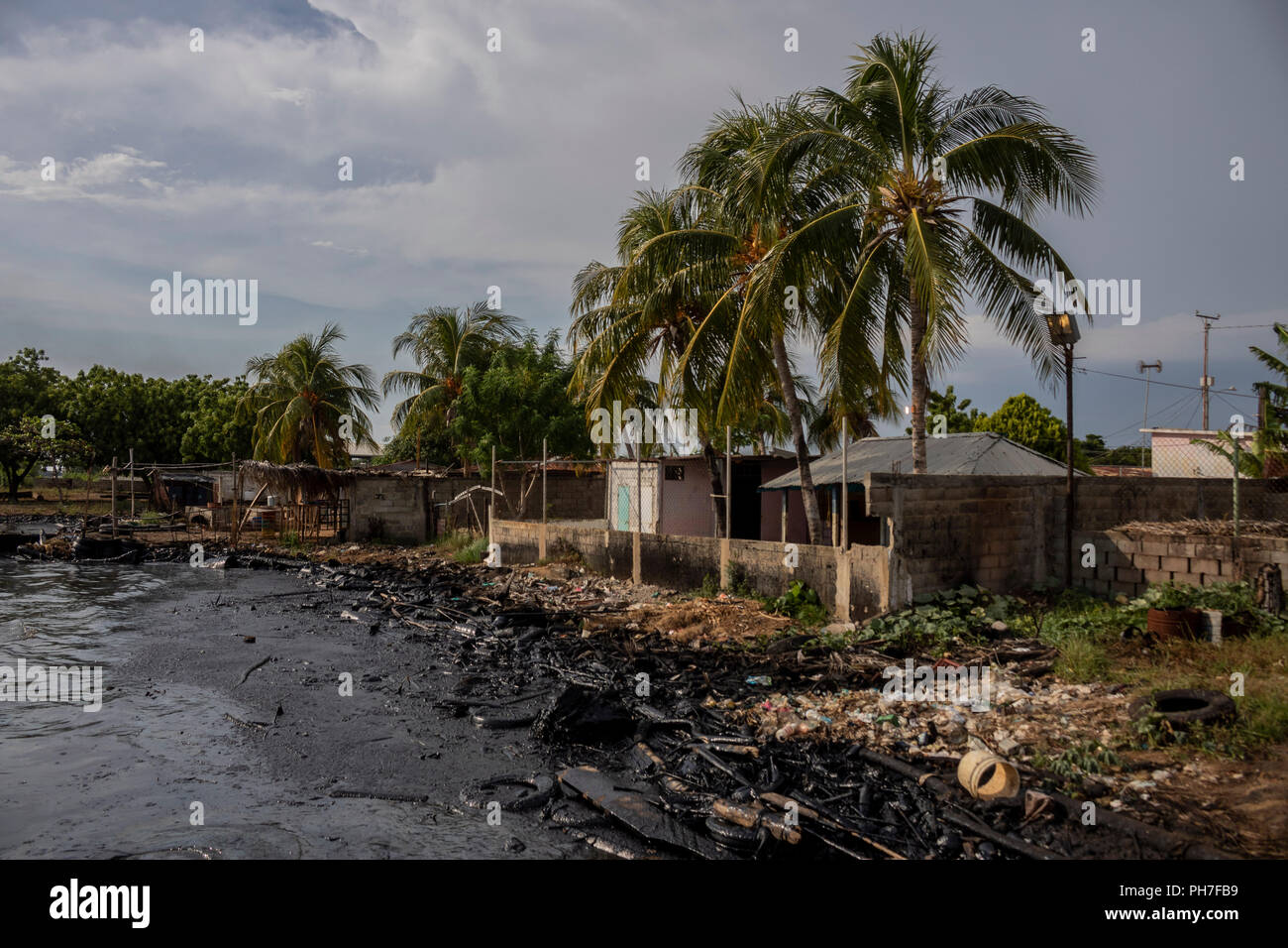 17 August 2018, Venezuela, Maracaibo: Shore of Lake Maracaibo polluted by oil and garbage. Underneath the lake are large deposits from which the state-owned Venezuelan company PDVSA produces oil and gas. Oil pipelines are already leaking there. However, the pollution of the lake seems to have become chronic. There are hardly any official figures on this, given the situation, which is strictly controlled by the national regime. Venezuela - once the richest country in South America and blessed with the world's largest oil reserves - has been increasingly plundering since the beginning of the yea Stock Photo