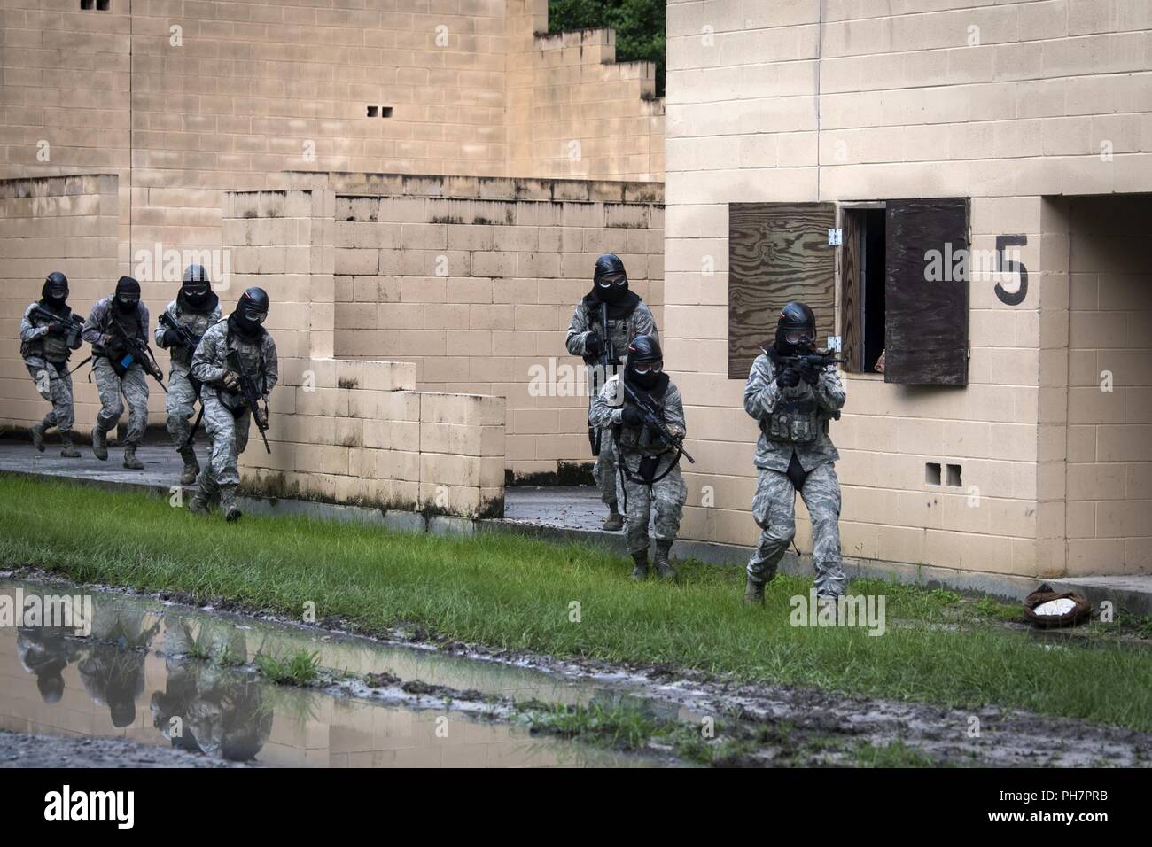 Airmen from the 23d Security Forces Squadron (SFS) run to the next building while providing cover fire during a Force on Force training scenario, June 29, 2018, at Moody Air Force Base, Ga. This training was held to ensure SFS Airmen are proficient in various tactics and procedures such as: building clear out, team movements, hostage rescue and properly applying cover fire. The scenario required Airmen to maneuver through multiple buildings to rescue a simulated victim guarded by opposing forces. Stock Photo