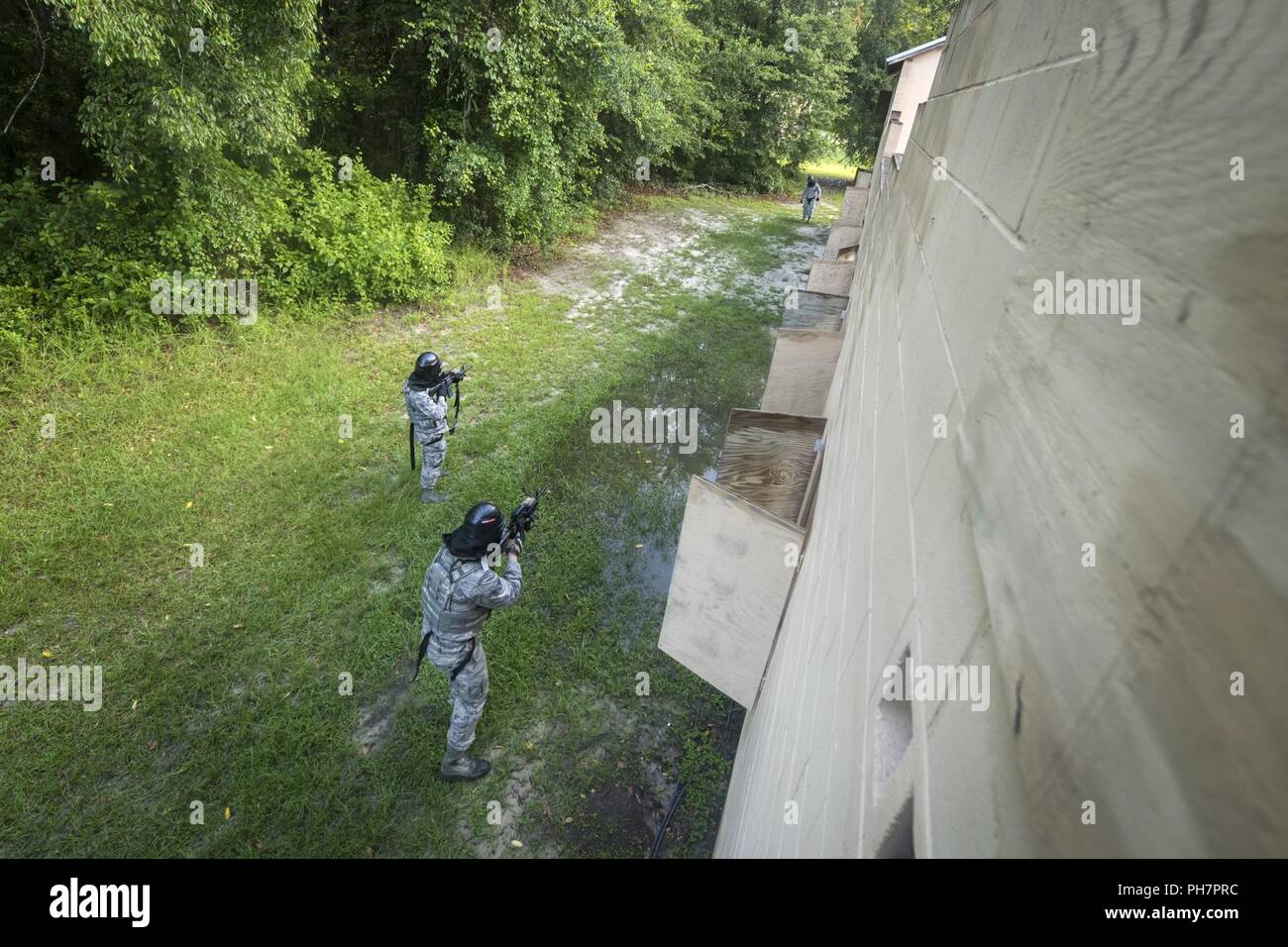 Airmen from the 23d Security Forces Squadron (SFS) take aim at an opposing assailant during a Force on Force training scenario, June 29, 2018, at Moody Air Force Base, Ga. This training was held to ensure SFS Airmen are proficient in various tactics and procedures such as: building clear out, team movements, hostage rescue and properly applying cover fire. The scenario required Airmen to maneuver through multiple buildings to rescue a simulated victim guarded by opposing forces. Stock Photo