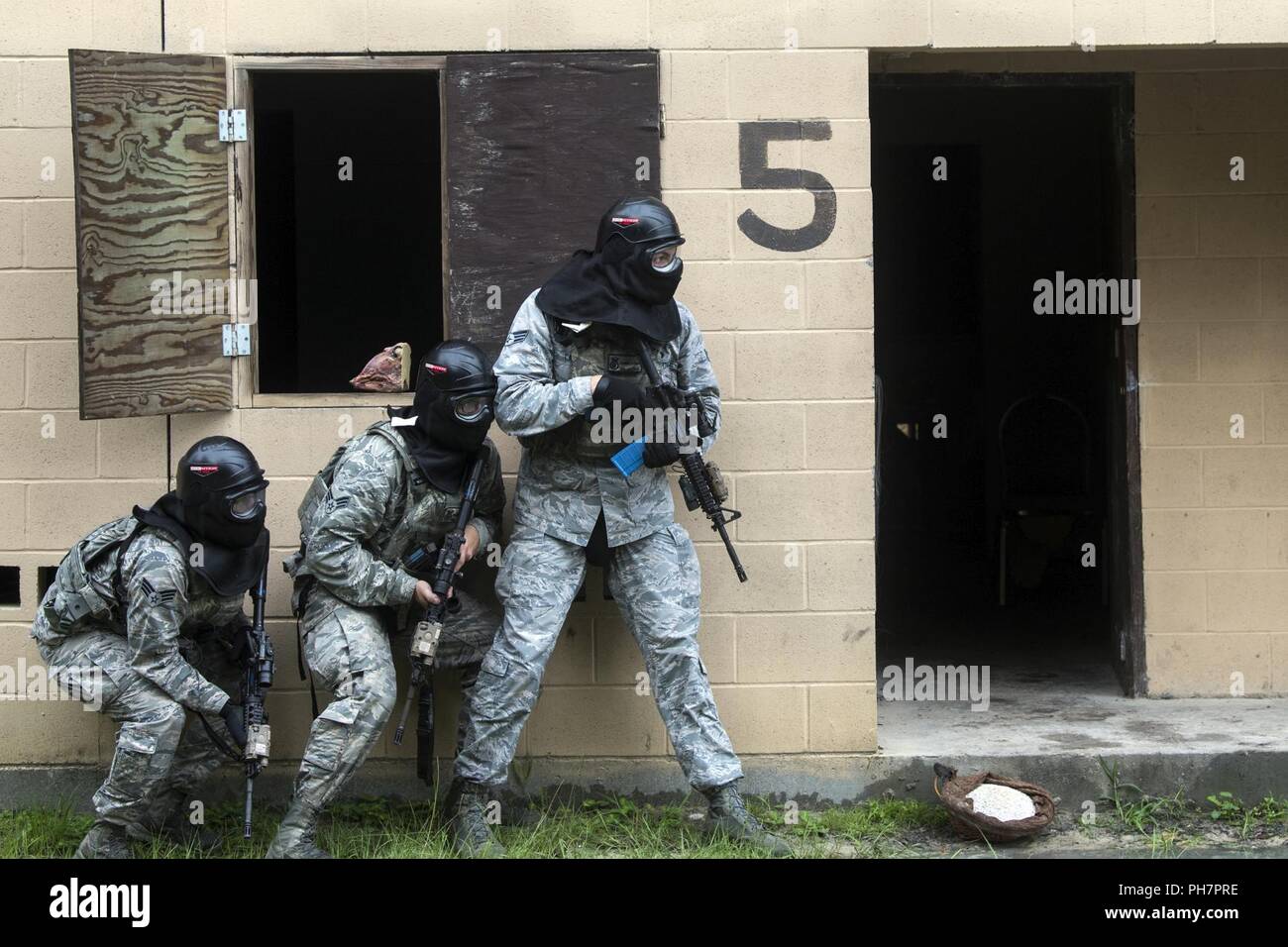 Airmen from the 23d Security Forces Squadron (SFS) prepare to clear a building during a Force on Force training scenario, June 29, 2018, at Moody Air Force Base, Ga. This training was held to ensure SFS Airmen are proficient in various tactics and procedures such as: building clear out, team movements, hostage rescue and properly applying cover fire. The scenario required Airmen to maneuver through multiple buildings to rescue a simulated victim guarded by opposing forces. Stock Photo