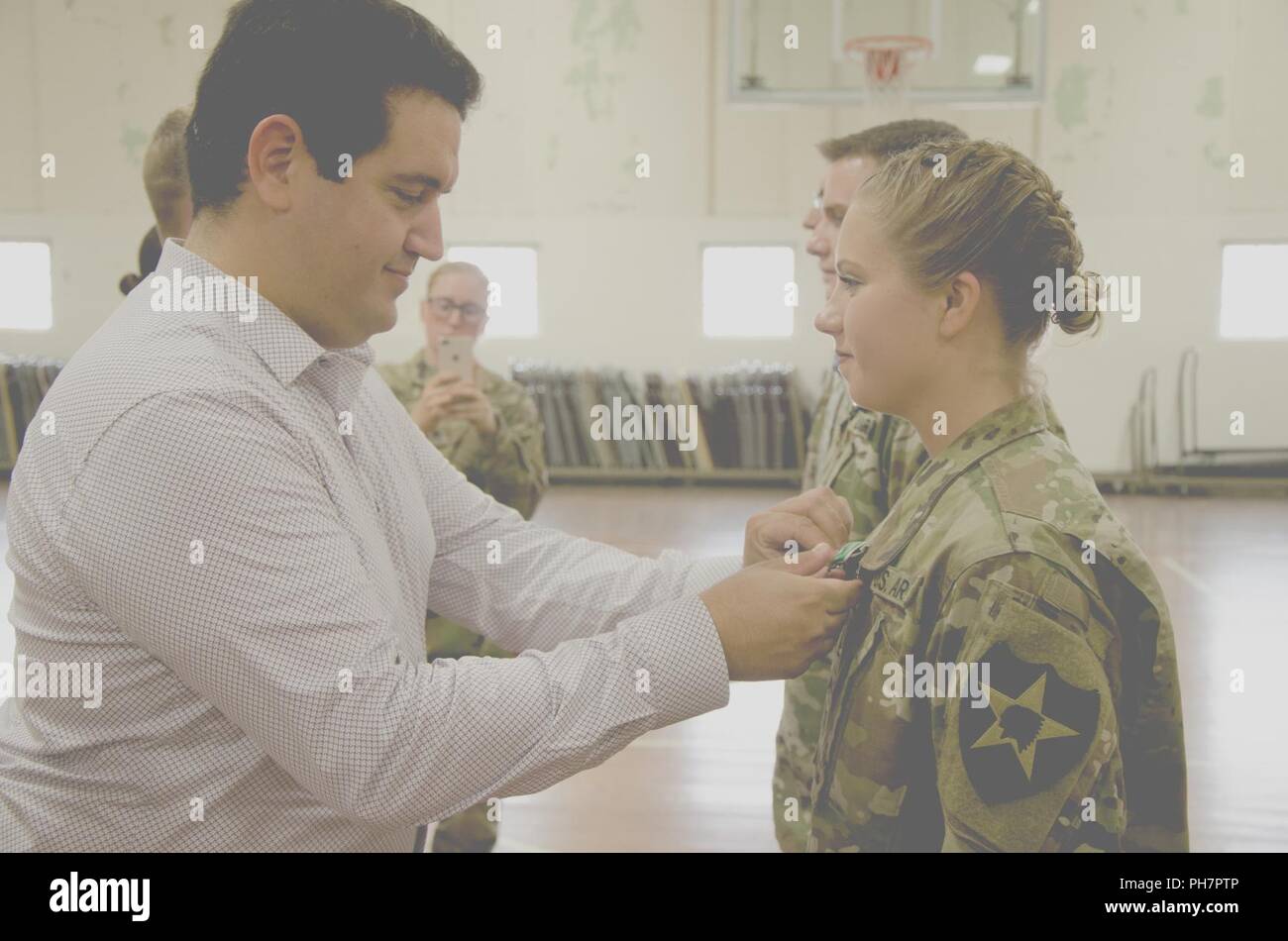 Pvt. Gracie, Medical Section, Headquarters and Headquarters Battery, 2nd Battalion, 146th Field Artillery Regiment, 81st Stryker Brigade Combat Team, receives an Army Achievement Medal from Ayoub Soulami, the father of the a little girl’s life that she had saved, June 30, 2018, at the National Guard Armory, Olympia, Wash. Hilinski saved the girl by administering cardiopulmonary resuscitation when her medical team made happened upon the emergency during a routine fuel stop, on April 6, 2018. Stock Photo