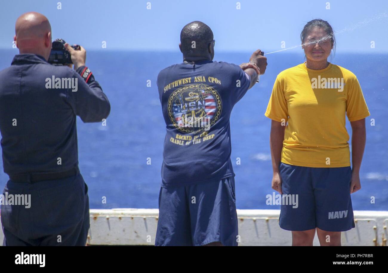 MEDITERRANEAN SEA (June 28 2018) Mass Communication Specialist 2nd Class Lyle Wilkie III, left, takes a photo of Chief Master-at-Arms Bernard Hyppolite spraying Ensign Genelle Arandia, from Gainesville, Florida, with oleoresin capsicum spray during security reaction force training aboard the San Antonio-class amphibious transport dock ship USS New York (LPD 21) June 28, 2018. New York, homeported in Mayport, Florida, is conducting naval operations in the U.S. 6th Fleet area of operations in support of U.S. national security interest in Europe and Africa. Stock Photo