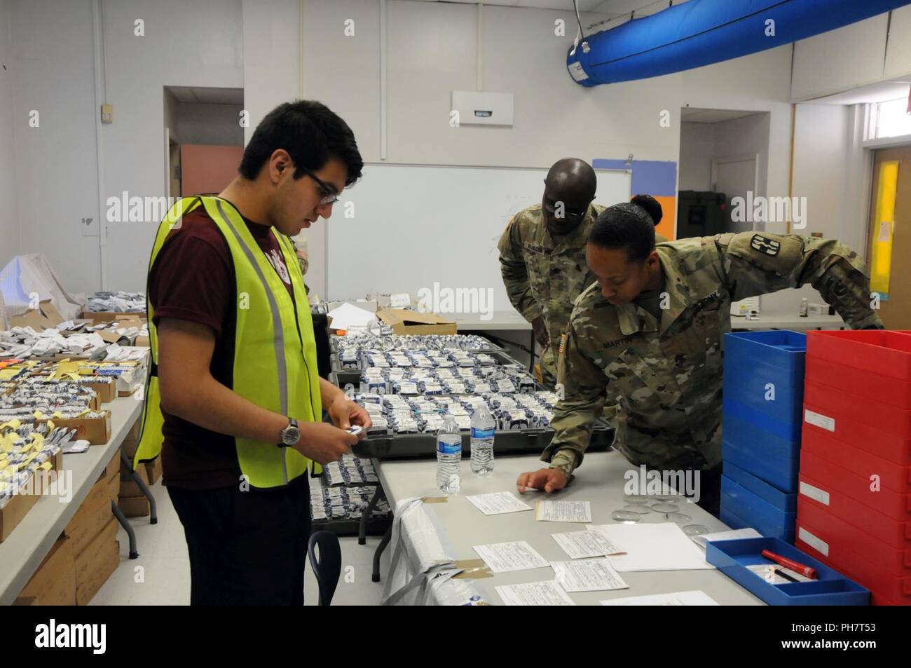 (LEFT TO RIGHT) Volunteer Juan Mata, a recently graduated Socorro High School, assists Sgt. Christen Martin, an optical laboratory specialist assigned to 31st Combat Support Hospital and Spc. Kodjo Koukoua, an Army Reserve optical laboratory specialist assigned to 7252nd Medical Support Unit, in processing new eye prescriptions for eyeglass fabrication at Escontrias Early Childhood Center in Socorro, Texas.  Martin and Koukoua are two of approximately 50 U.S. Army Reserve and U.S. Army Soldiers who are working in partnership with the Texas A&M Colonias program to provide medical care to El Pas Stock Photo