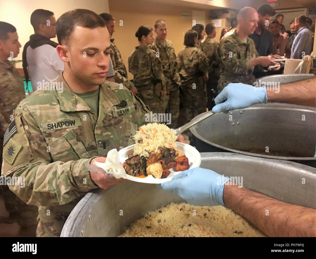 First Lt. Bryan Shapow, the aide-de-camp for Brig. Gen. John Lathrop, commander for Train, Advise and Assist Command-South, comprised of the 40th Infantry Division, California National Guard, and the 2nd Infantry Brigade Combat Team, 4th Infantry Division, receives traditional Afghan food during Eid al-Fitr, a celebration, on Kandahar Airfield, Afghanistan, June 18. Eid al-Fitr, known as Eid for short, is a celebration marking the end of Ramadan, locally known as Ramazan, Islam’s holy month of fasting. Stock Photo