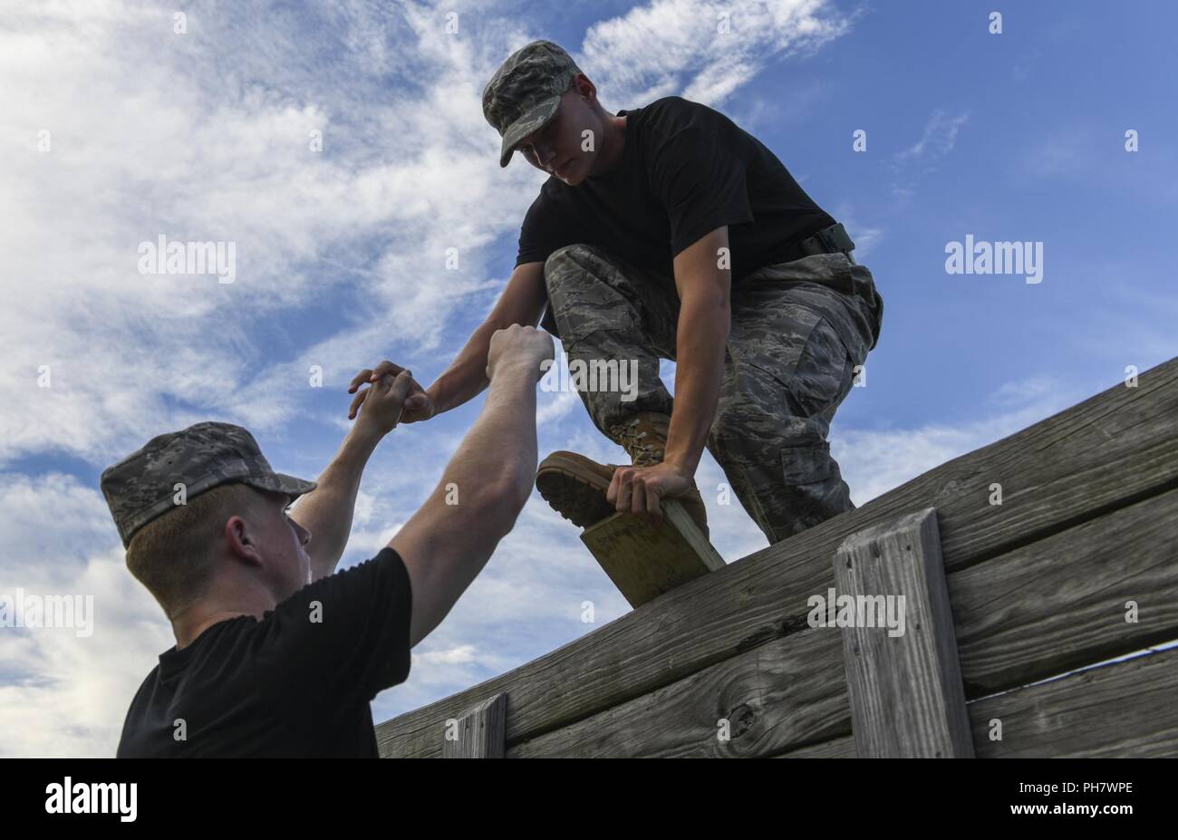 A Junior ROTC cadet helps a fellow cadet on an obstacle course during