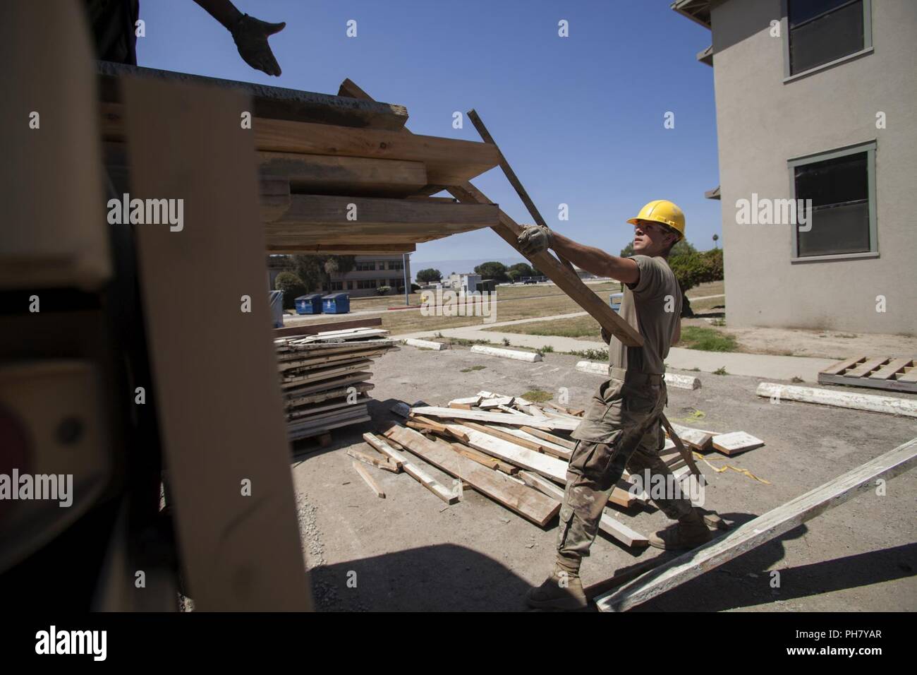U.S. Army Pfc. Dominic Steveley, a carpentry/masonry specialist with the 315th Vertical Construction Company, 250th Military Intelligence Battalion, 100th Troop Command, 40th Infantry Division, California National Guard, loads wood into the back of a vehicle, June 27, 2018, while working on construction projects at Joint Forces Training Base, Los Alamitos, California. Engineers from the 315th VCC are working on renovations and creating new infrastructure, including sidewalks and trash enclosures, during their annual training. Stock Photo