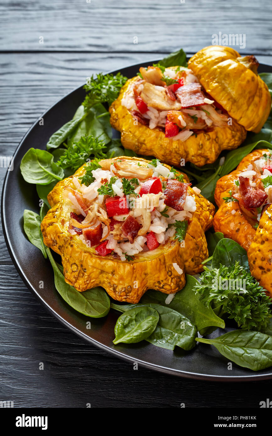 baked Patty Pan squash stuffed with rice, fried chicken meat, crispy fried bacon, bell pepper and served with green fresh spinach leaves and parsley o Stock Photo