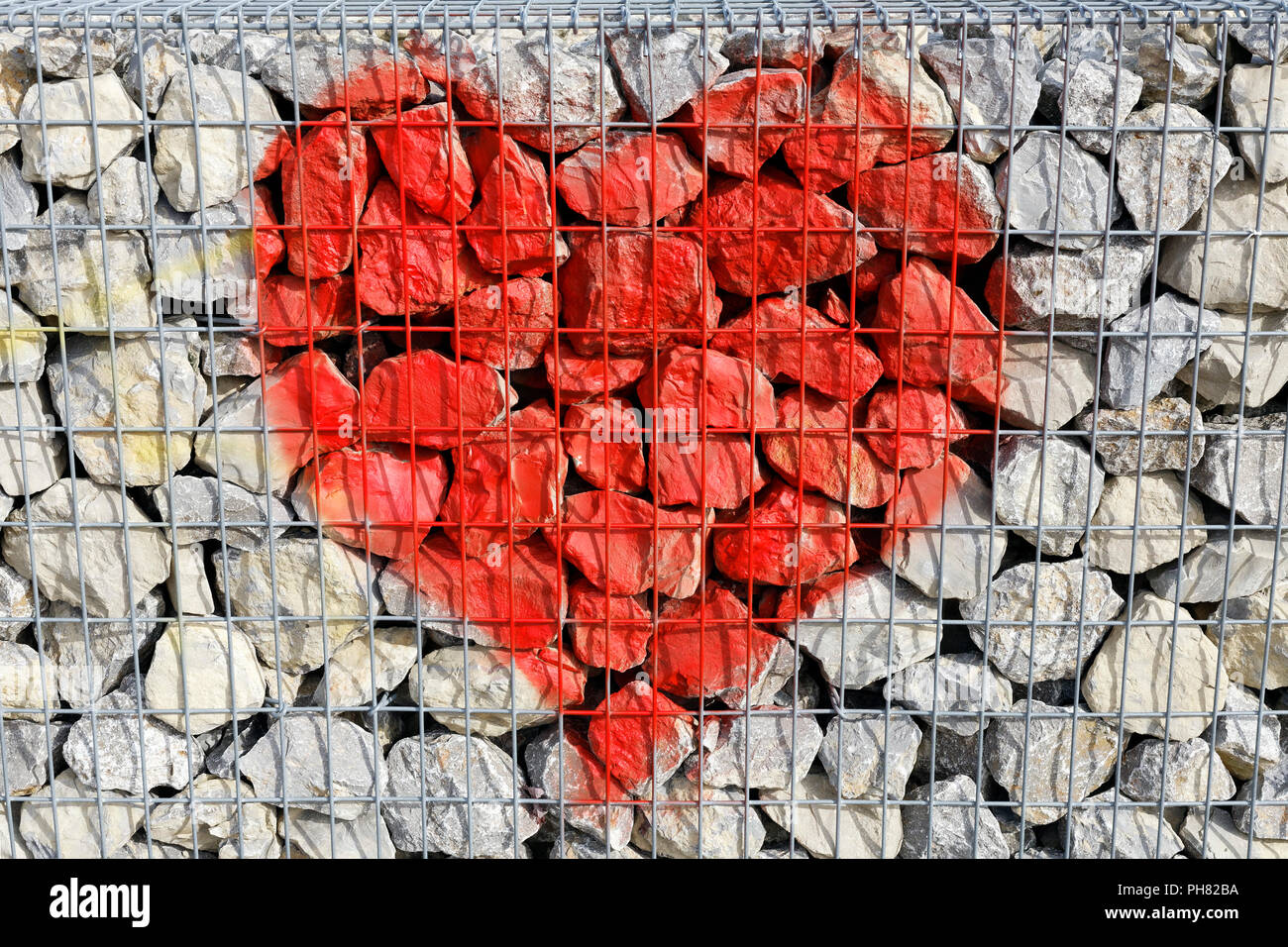 Red heart behind wireframe, painted on stones, Gabion, Düsseldorf, North Rhine-Westphalia, Germany Stock Photo