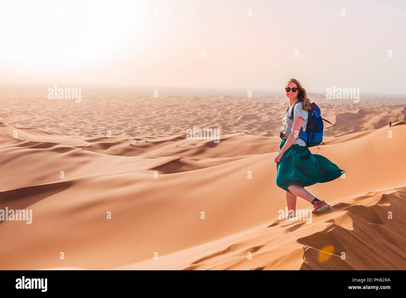 Female hiker on a red sand dune in the desert, dune landscape Erg Chebbi, Merzouga, Sahara, Morocco Stock Photo
