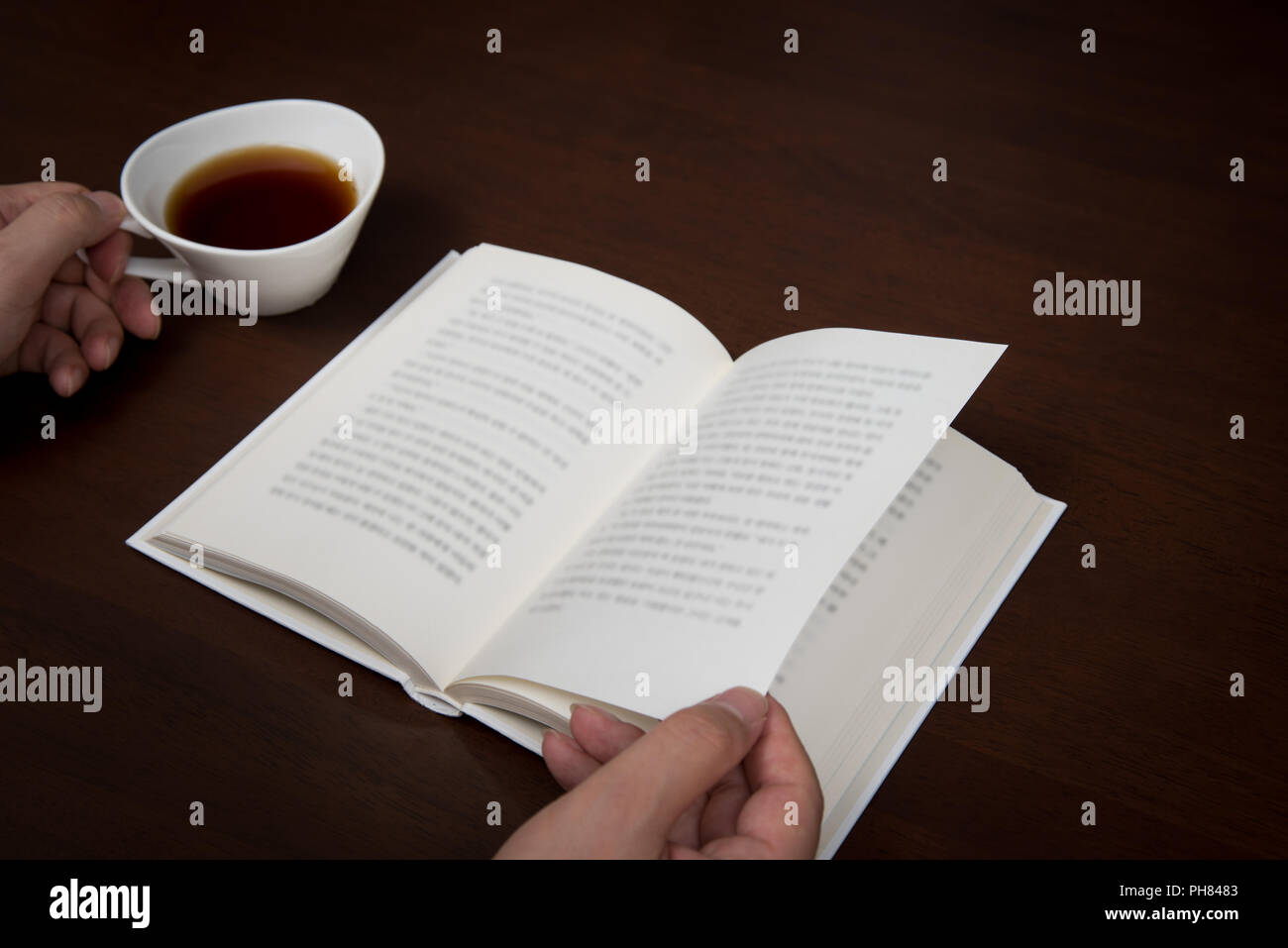 the man's hand reading with a cup of coffee in one hand Stock Photo - Alamy