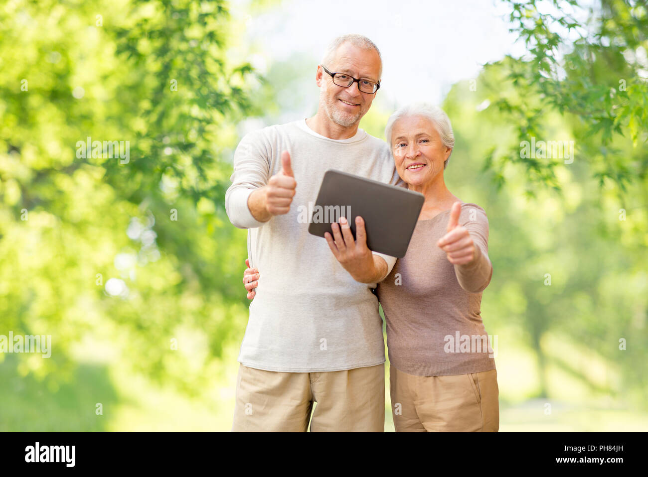 senior couple with tablet pc showing thumbs up Stock Photo