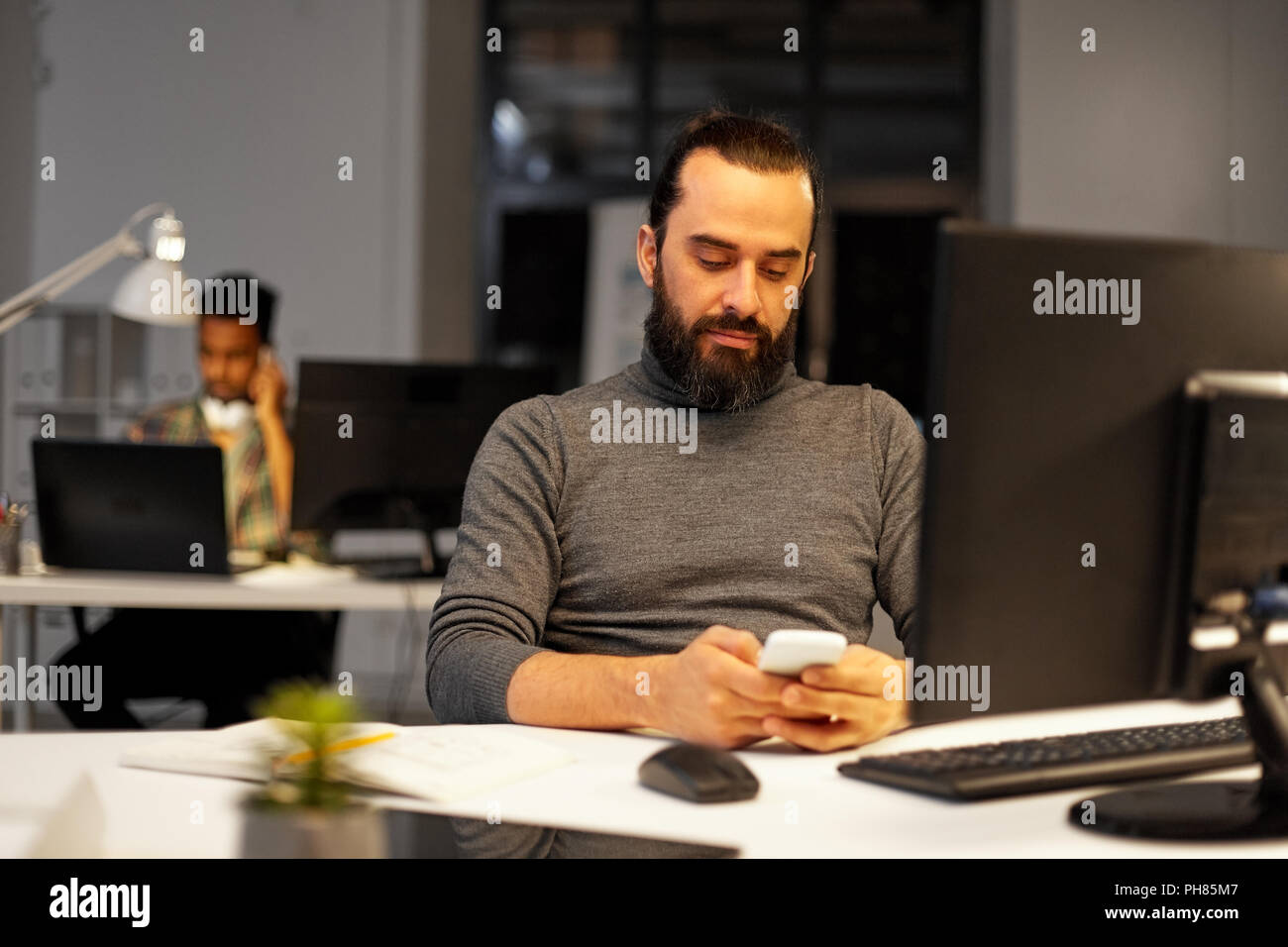 creative man with smartphone at night office Stock Photo