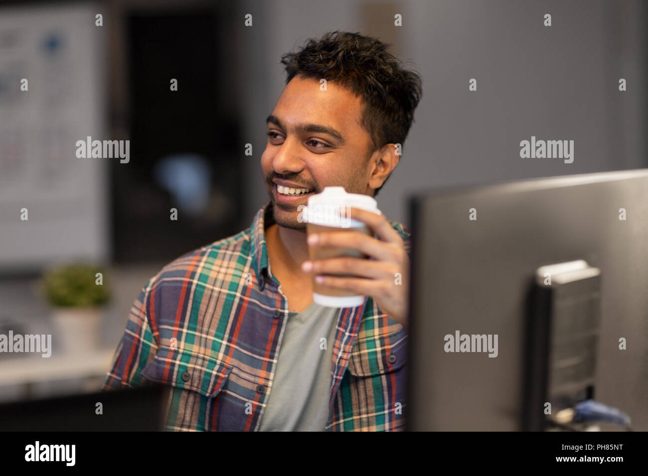 happy creative man drinking coffee at night office Stock Photo