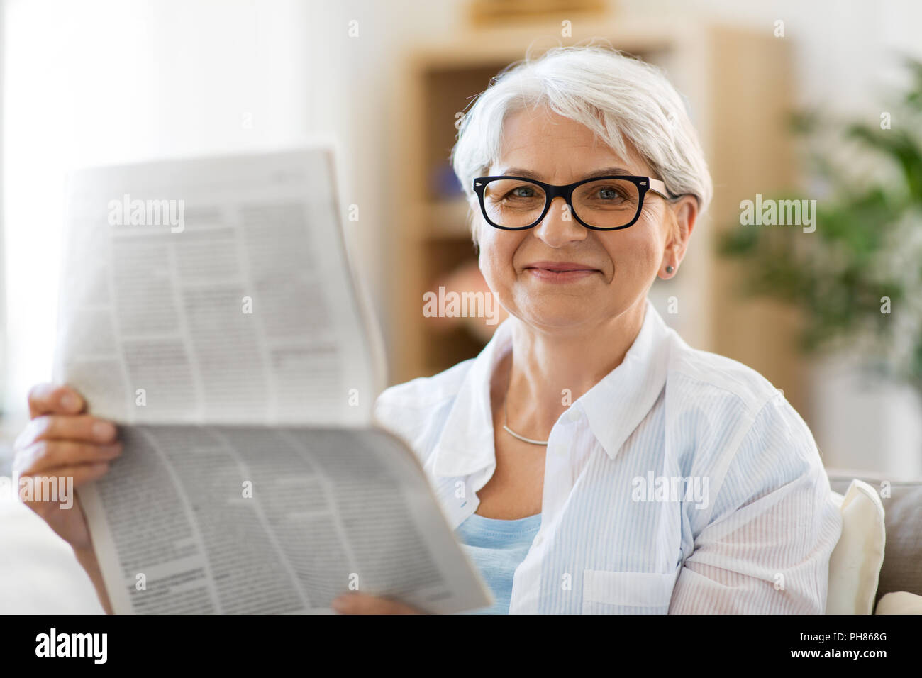 portrait of senior woman reading newspaper at home Stock Photo